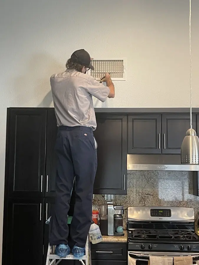 Technician inspecting an air vent during HVAC service in Pasadena